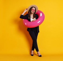 Photo of Businesswoman with inflatable ring, straw hat and sunglasses on orange background