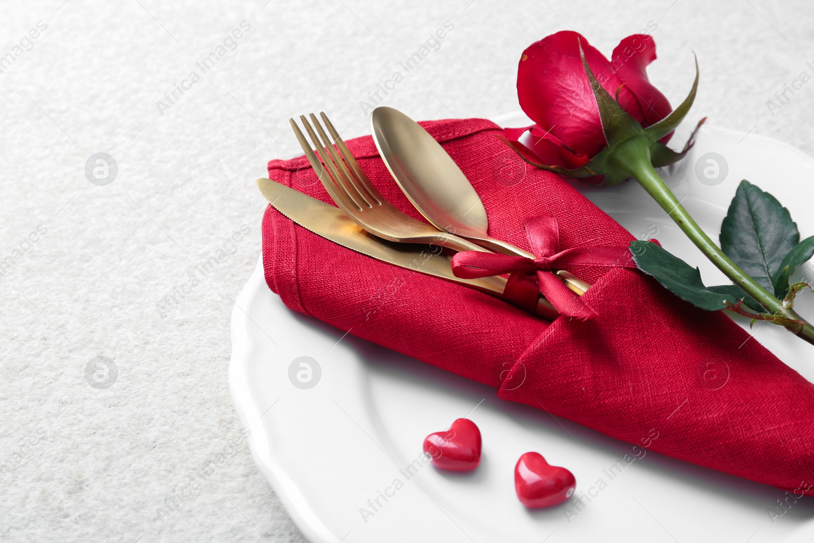 Photo of Romantic place setting with red rose on white table, closeup. Valentine's day celebration