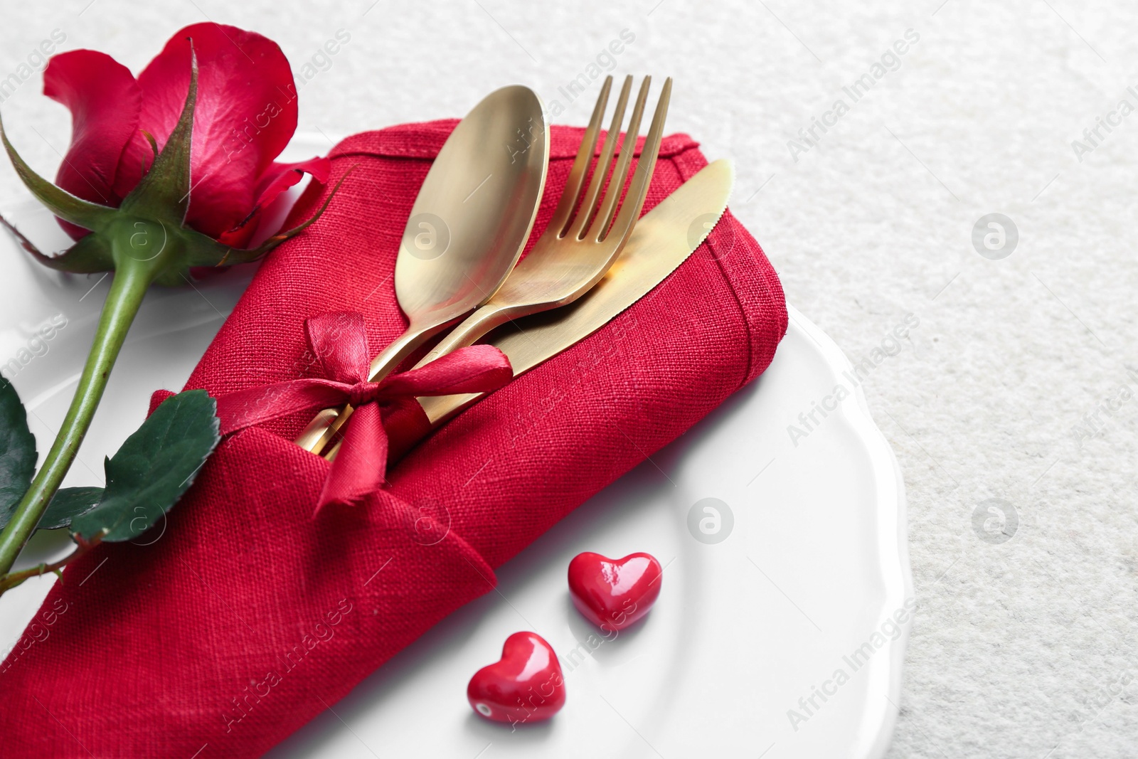 Photo of Romantic place setting with red rose on white table, closeup. Valentine's day celebration