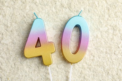 Photo of 40th birthday. Number shaped candles on light textured background, top view