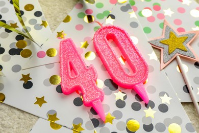 Photo of 40th birthday. Number shaped candles, party decor and confetti on light textured background, closeup