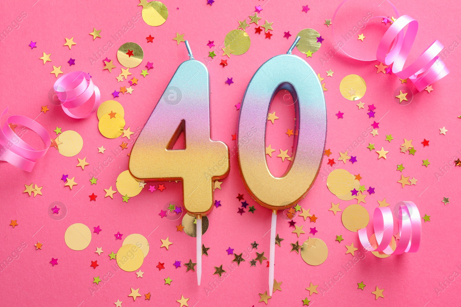 Photo of 40th birthday. Number shaped candles and confetti on pink background, flat lay