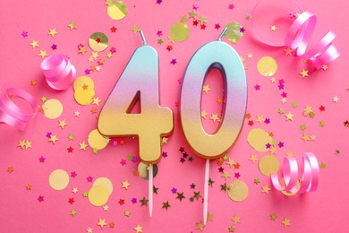 Photo of 40th birthday. Number shaped candles and confetti on pink background, flat lay