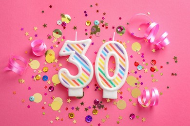 Photo of 30th birthday. Number shaped candles and confetti on pink background, flat lay