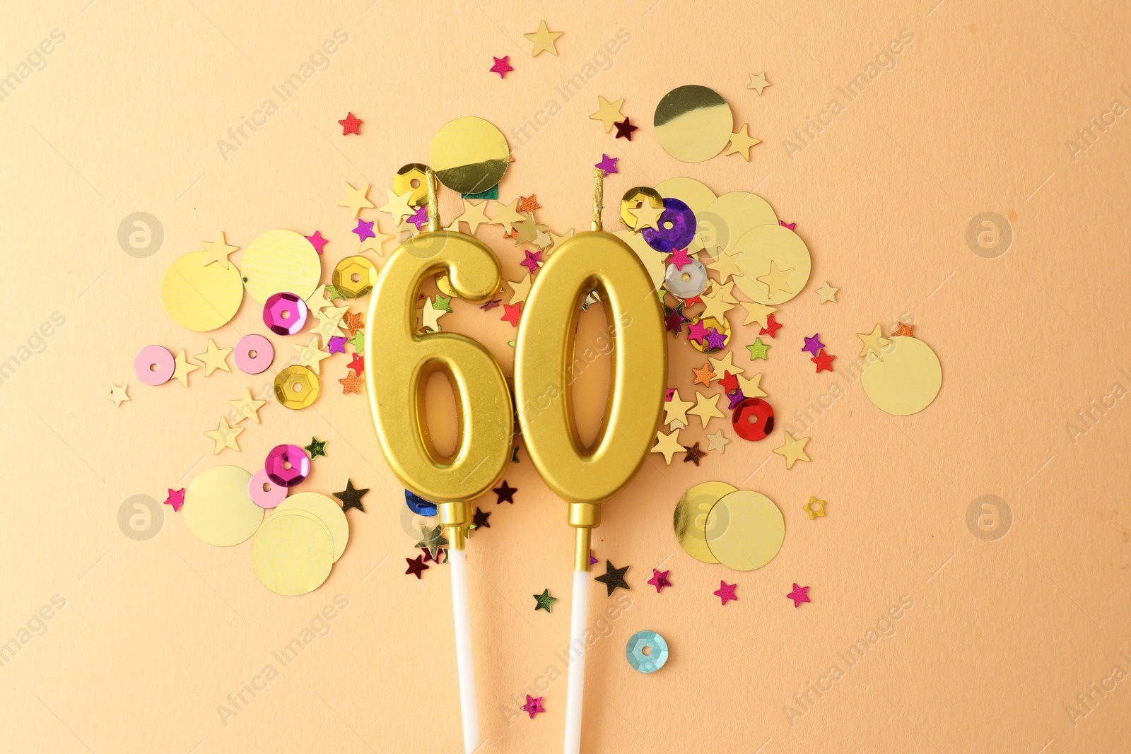 Photo of 60th birthday. Number shaped candles and confetti on beige background, flat lay