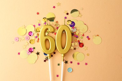 Photo of 60th birthday. Number shaped candles and confetti on beige background, flat lay