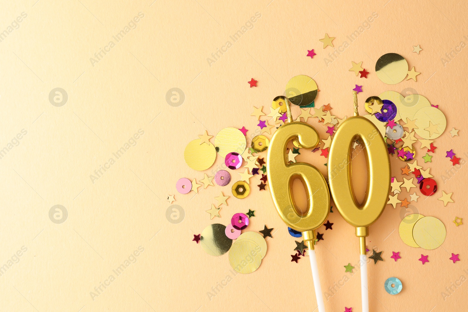 Photo of 60th birthday. Number shaped candles and confetti on beige background, flat lay. Space for text