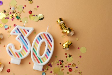 Photo of 30th birthday. Number shaped candles and confetti on beige background, flat lay. Space for text