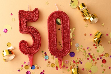 Photo of 50th birthday. Number shaped candles and confetti on beige background, flat lay