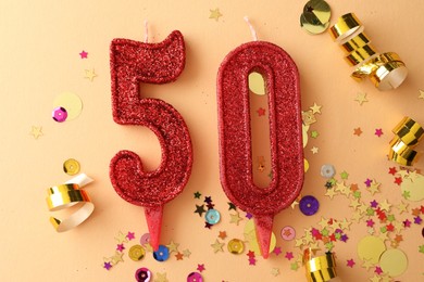 Photo of 50th birthday. Number shaped candles and confetti on beige background, flat lay