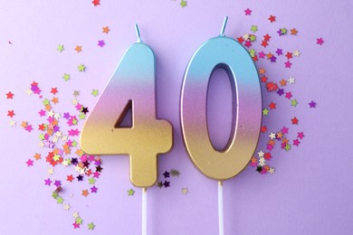 Photo of 40th birthday. Number shaped candles and confetti on violet background, flat lay