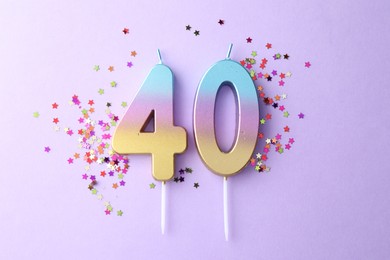 Photo of 40th birthday. Number shaped candles and confetti on violet background, flat lay