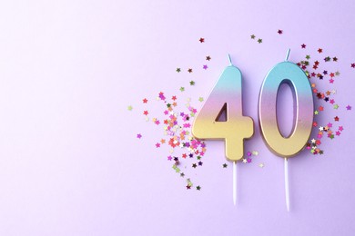 Photo of 40th birthday. Number shaped candles and confetti on violet background, flat lay. Space for text