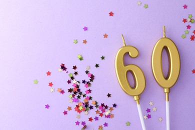 Photo of 60th birthday. Number shaped candles and confetti on violet background, flat lay. Space for text