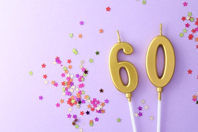 Photo of 60th birthday. Number shaped candles and confetti on violet background, flat lay