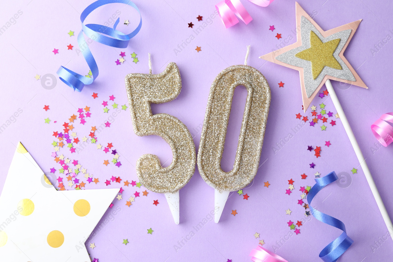 Photo of 50th birthday. Number shaped candles, confetti and party decor on violet background, flat lay