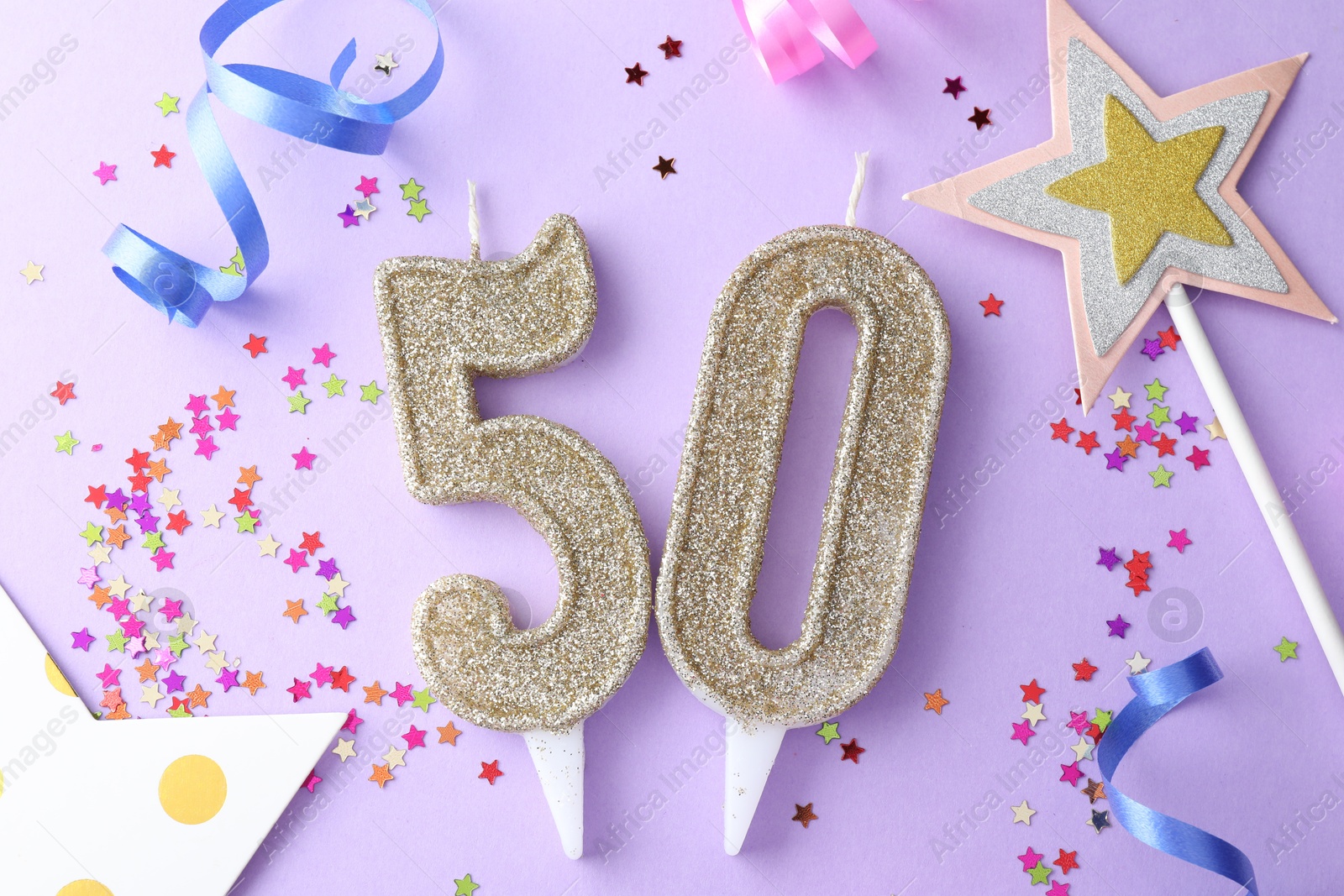 Photo of 50th birthday. Number shaped candles, confetti and party decor on violet background, flat lay