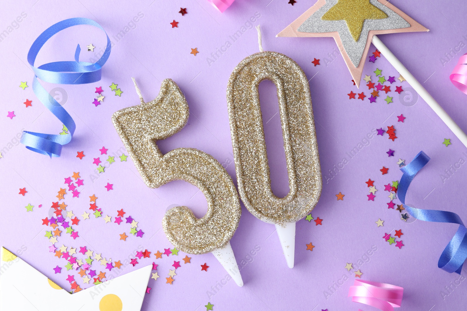 Photo of 50th birthday. Number shaped candles, confetti and party decor on violet background, flat lay