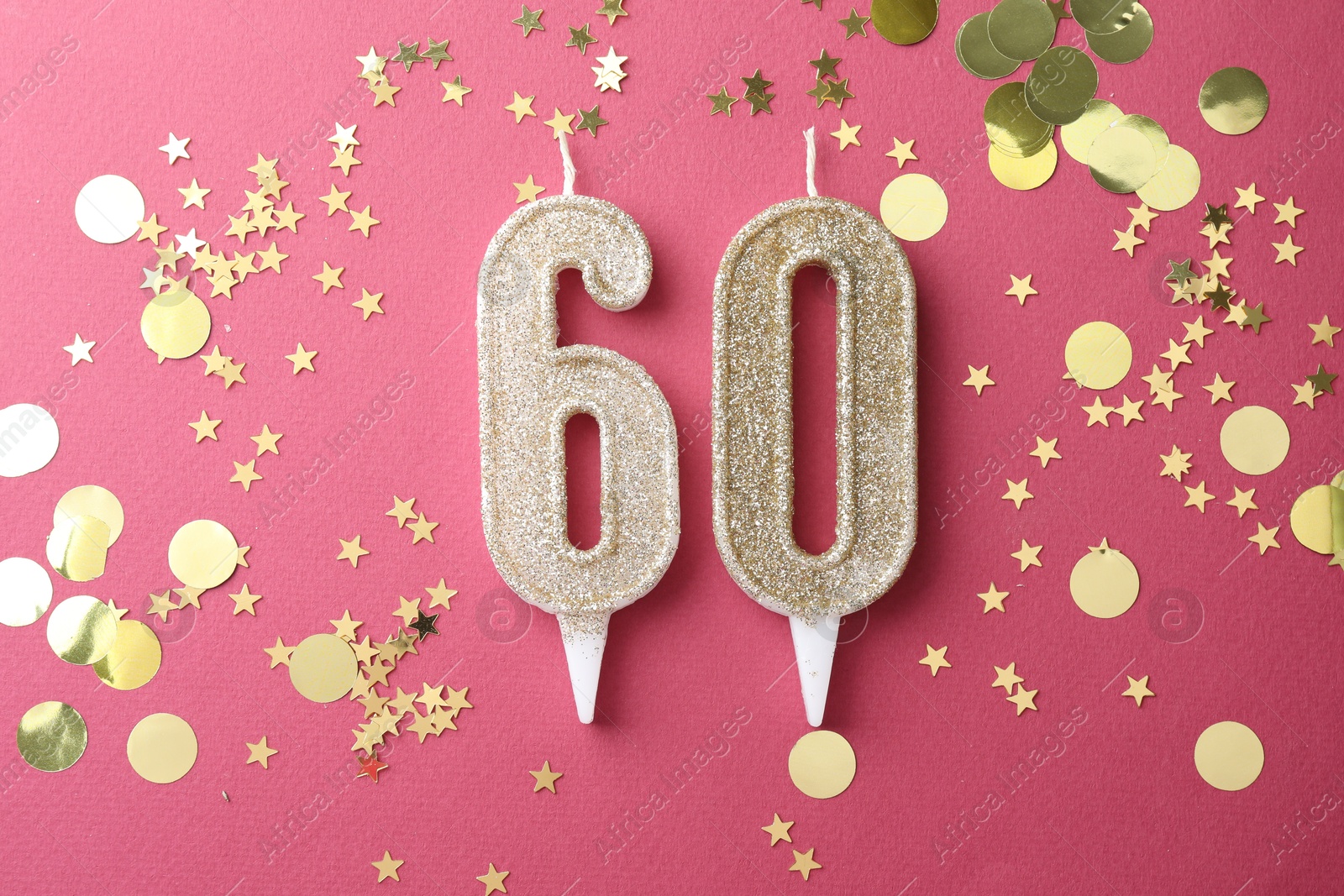 Photo of 60th birthday. Number shaped candles and confetti on pink background, flat lay