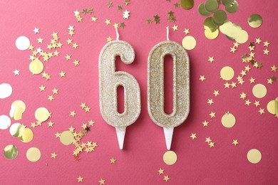 Photo of 60th birthday. Number shaped candles and confetti on pink background, flat lay