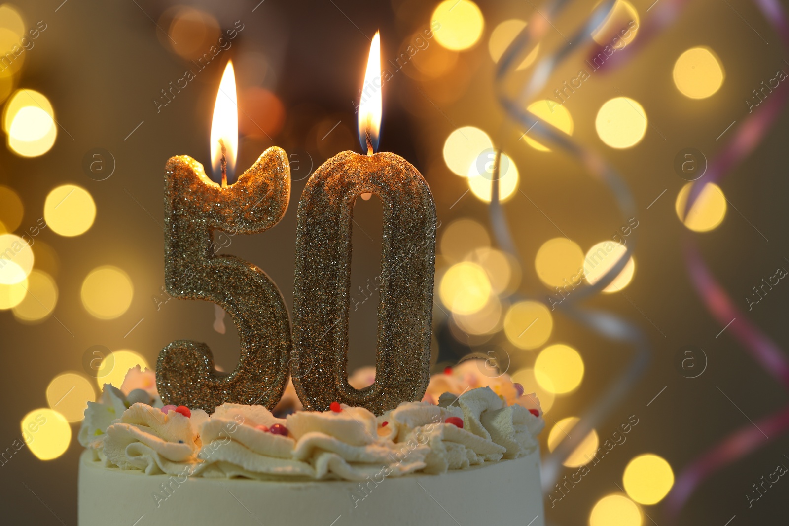 Photo of 50th birthday. Burning number shaped candles on cake against blurred background with lights, closeup and space for text. Bokeh effect