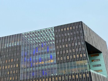 Beautiful building with many windows against blue sky, low angle view