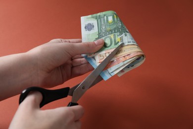 Photo of Woman cutting euro banknotes on brown background, closeup. Space for text