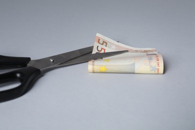 Photo of Scissors with euro banknote on gray background, closeup