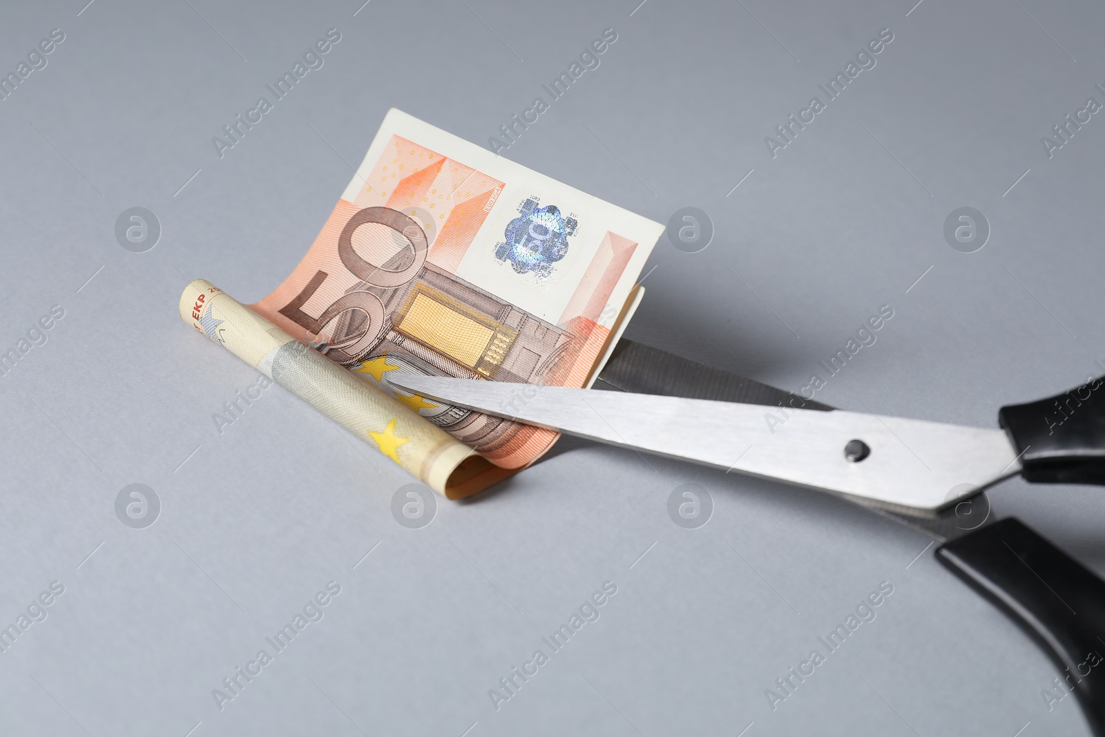 Photo of Scissors with euro banknote on gray background, closeup