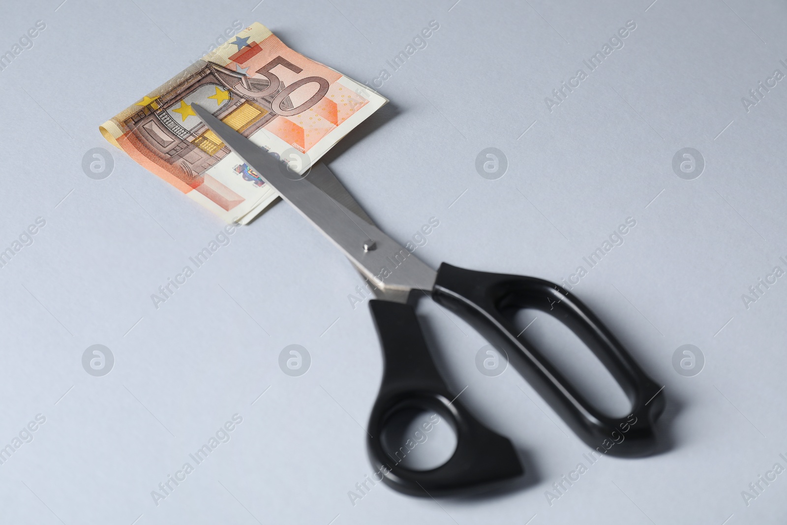 Photo of Scissors with euro banknote on gray background, closeup