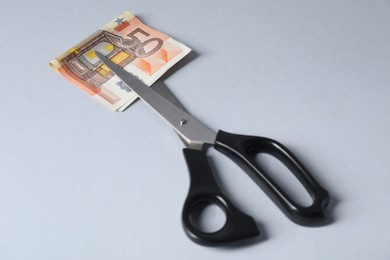 Photo of Scissors with euro banknote on gray background, closeup