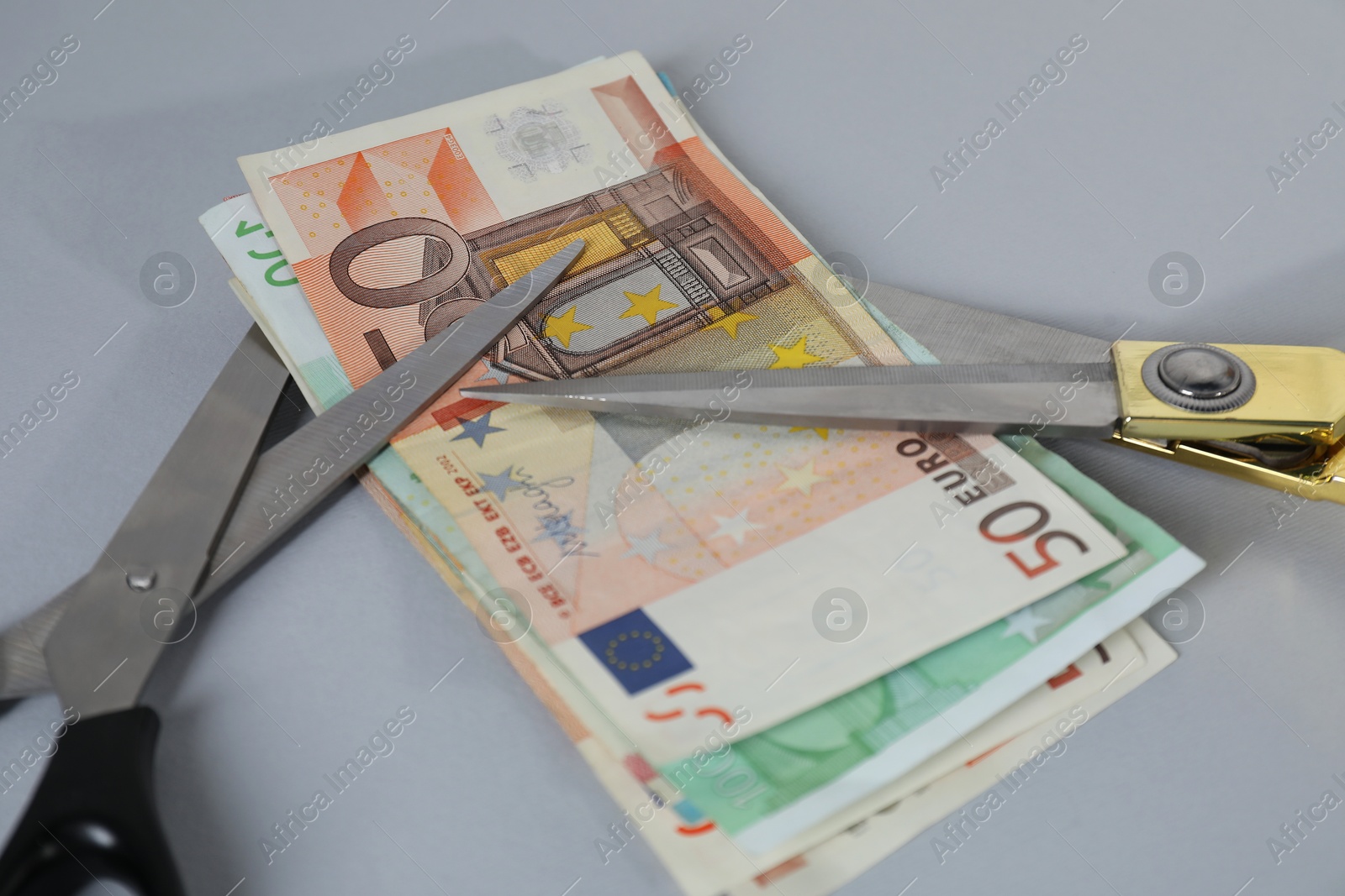 Photo of Euro banknotes and scissors on gray background, closeup