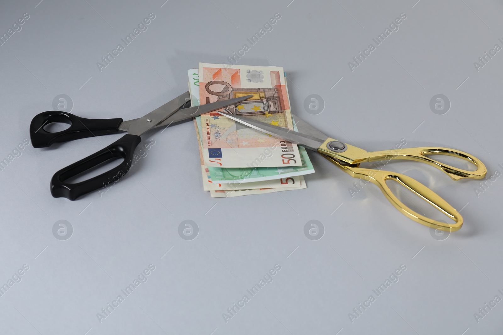 Photo of Euro banknotes and scissors on gray background