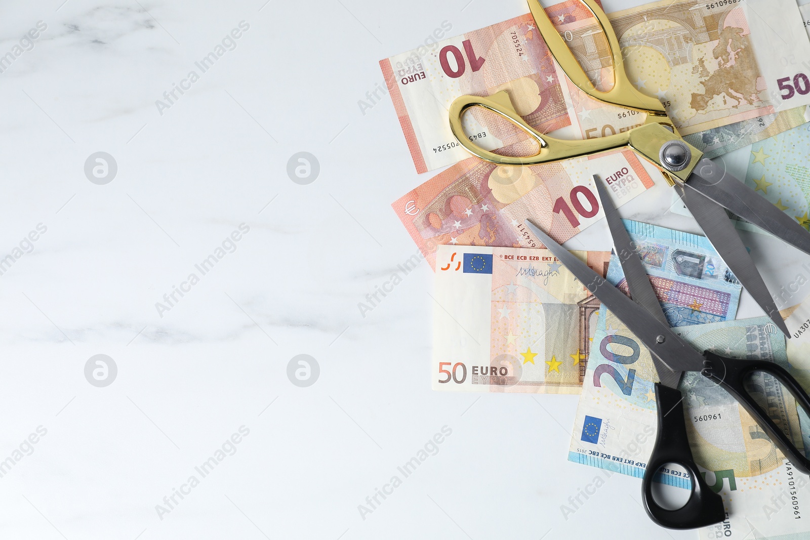 Photo of Euro banknotes and scissors on light marble table, flat lay. Space for text