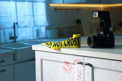 Photo of Camera, yellow crime scene tape and bloody handprint on chest of drawers in kitchen. Forensic expertise