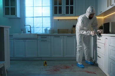 Photo of Forensic expert taking fingerprints from countertop with brush at crime scene indoors, space for text