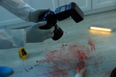 Photo of Forensic expert with camera working at crime scene in dark room, closeup