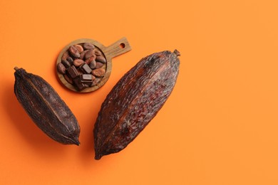 Photo of Cocoa pods and beans on orange background, top view