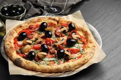 Photo of Tasty pizza with mushrooms, olives, arugula and cutter on black table, closeup