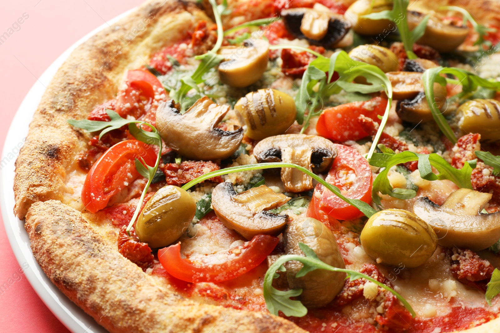 Photo of Tasty pizza with mushrooms, olives and arugula on red background, closeup