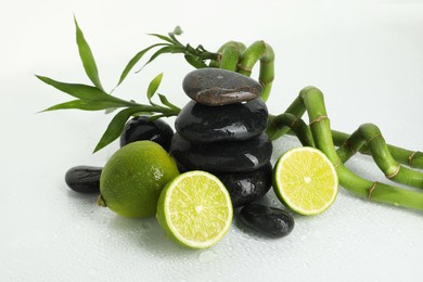 Photo of Spa composition with limes, massage stones and bamboo stems on wet surface