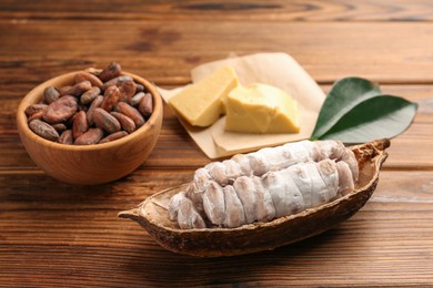 Photo of Cocoa pod with beans and butter on wooden table, closeup