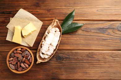 Photo of Cocoa pod with beans and butter on wooden table, flat lay. Space for text