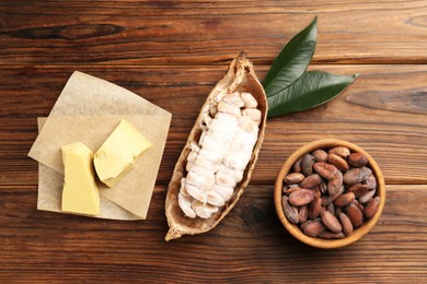 Photo of Cocoa pod with beans and butter on wooden table, flat lay