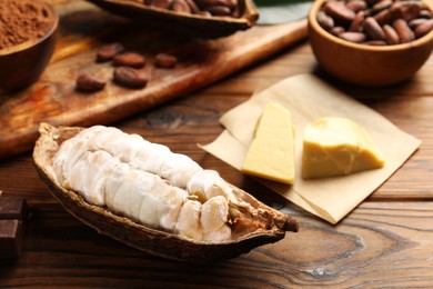 Photo of Cocoa pod with beans and butter on wooden table, closeup