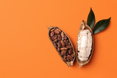 Photo of Cocoa pods with beans on orange background, top view. Space for text