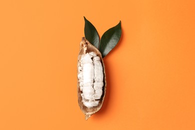 Photo of Cocoa pod with beans on orange background, top view