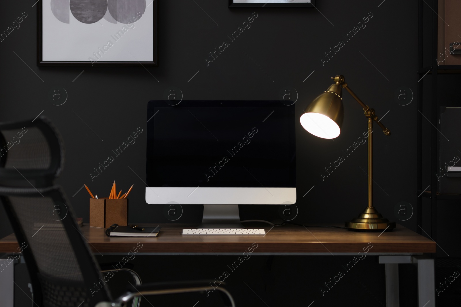 Comfortable workplace with computer and lamp on wooden desk in home office Photo of Comfortable workplace with computer and lamp on wooden desk in home office
