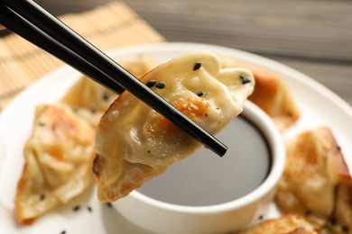 Photo of Eating fried gyoza dumplings at wooden table, closeup