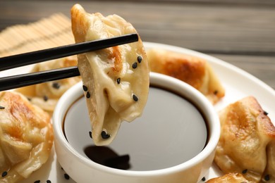 Eating fried gyoza dumplings at wooden table, closeup